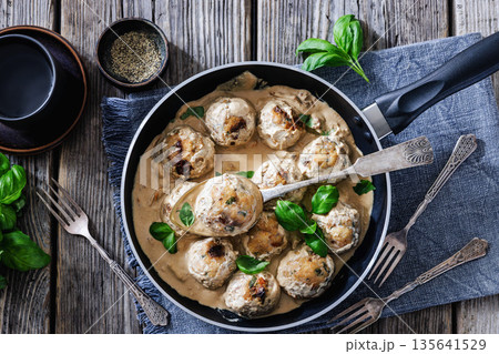 Chicken meatball on spoon over pan with sauce Chicken meatball on spoon over pan with sauce 135641529
