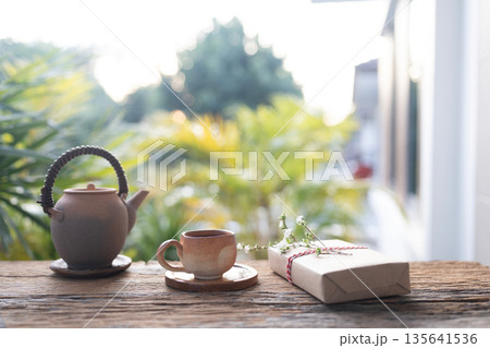 Old earthenware tea pot and gift box with flower on balcony outdoor in winter under Old earthenware tea pot and gift box with flower on balcony outdoor in winter under 135641536