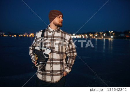 Standing and looking far away. A man is on the ice with his skates in winter 135642242