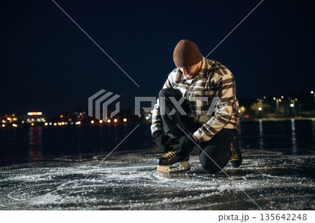 In checkered shirt and in hat. A man is on the ice with his skates in winter 135642248