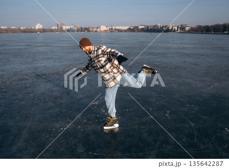 Riding on the frozen lake. A man is on the ice with his skates in winter 135642287