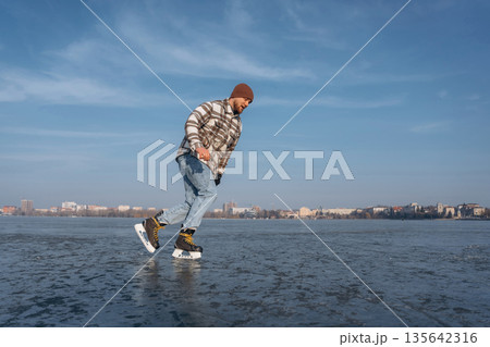 Riding on the frozen lake. A man is on the ice with his skates in winter 135642316