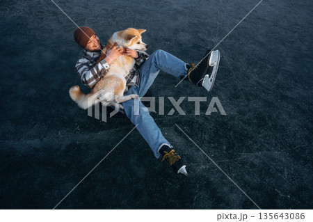 Human's best friend. Man with Akita Inu dog is on the ice with skates in winter 135643086