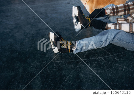 Top view, sitting. Man with Akita Inu dog is on the ice with skates in winter 135643136