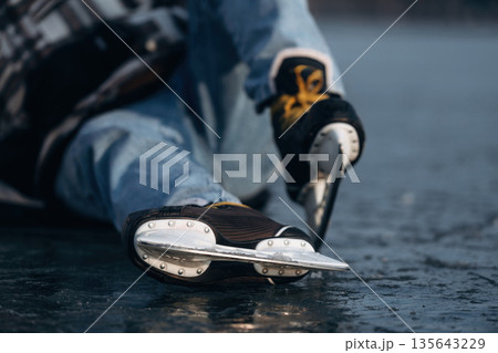 Sitting on the ice. Close up view of man that is with skates in winter Sitting on the ice. Close up view of man that is with skates in winter 135643229