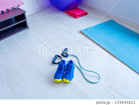 Sports shoes and resistance band on gym floor 135643821