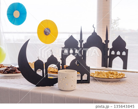 Eid Mubarak table with Ramadan sweets, dates, nuts and festive decor 135643845