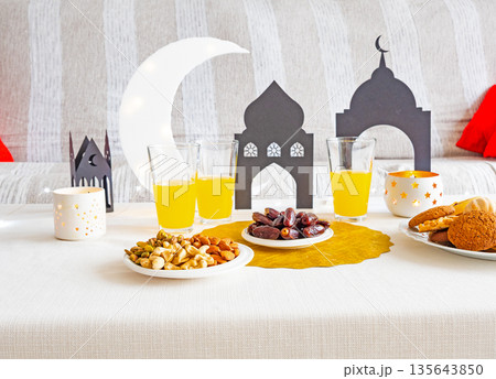 Eid Mubarak table with Ramadan sweets, dates, nuts and festive decor 135643850