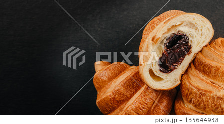 Chocolate filled croissant cut in half on dark background with copy space Chocolate filled croissant cut in half on dark background with copy space 135644938