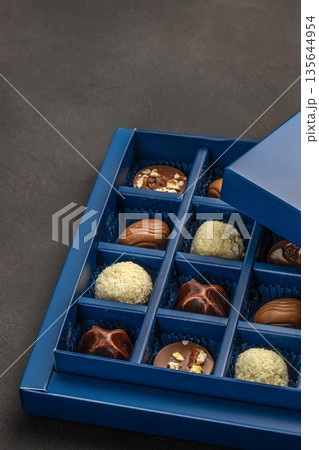 Luxury assorted chocolate pralines in blue gift box on dark background Luxury assorted chocolate pralines in blue gift box on dark background 135644954