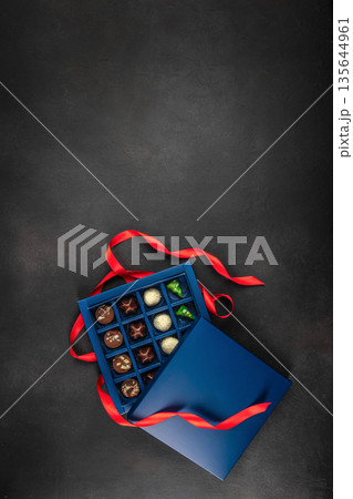 Luxury chocolate gift box with red ribbon on dark background Luxury chocolate gift box with red ribbon on dark background 135644961