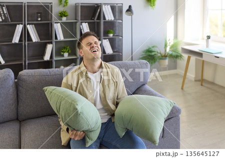 Stressed tenant blocking noise with cushions during neighbor disturbance at home Stressed tenant blocking noise with cushions during neighbor disturbance at home 135645127