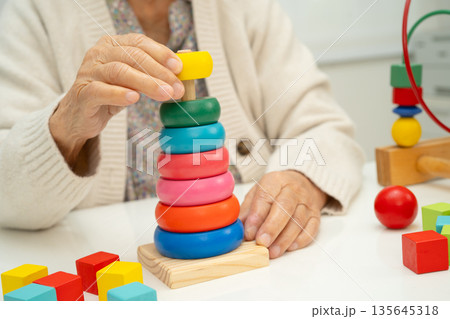 Asian elderly woman playing enhancing skill board game. 135645318