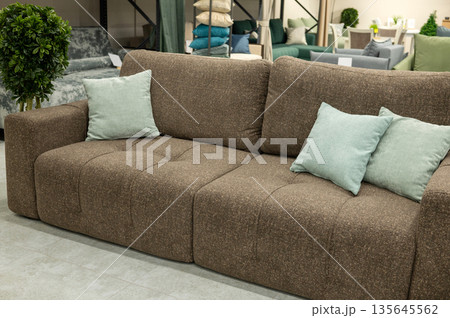 Cozy brown sofa with green accent pillows in modern living room setting Cozy brown sofa with green accent pillows in modern living room setting 135645562