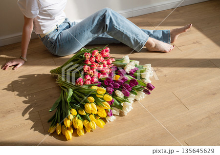 Female relaxing with colorful tulips on wooden floor 135645629