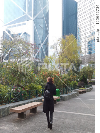 Woman walking with urban skyscrapers background in Hong Kong 135645734