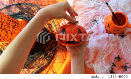 Handmade pumpkin painting on an orange background with a spider web Handmade pumpkin painting on an orange background with a spider web 135646006