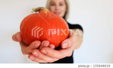 Beautiful blonde girl on a white background with a pumpkin in her hands Beautiful blonde girl on a white background with a pumpkin in her hands 135646019