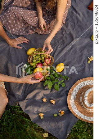 Capturing tactile moment as woman selects ripe fruit from basket Capturing tactile moment as woman selects ripe fruit from basket 135646024
