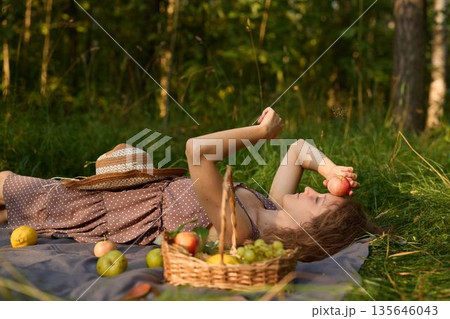 Serene scene of woman collecting harvest in sunny landscape Serene scene of woman collecting harvest in sunny landscape 135646043