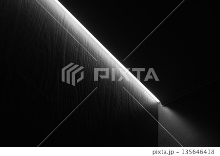 A dark, minimalist scene features a thin ceiling light 135646418