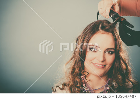 Hairdresser curling woman hair with iron curler. Hairdresser curling woman hair with iron curler. 135647487