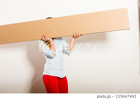 Woman moving into apartment carrying box. Woman moving into apartment carrying box. 135647491