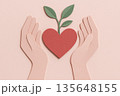 Paper cut hand holding heart with sprouting leaf gentle shadow tactile texture pastel pink dusty red natural green palette environment care love growth concept 135648155