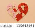 Broken heart shape crafted from red and pink paper piece arranged on beige background representing relationship breakup and heartbreak emotion for valentine day 135648161