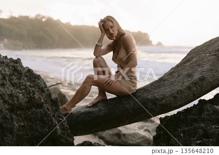 Blonde woman posing between coastal rocks on beach Blonde woman posing between coastal rocks on beach 135648210