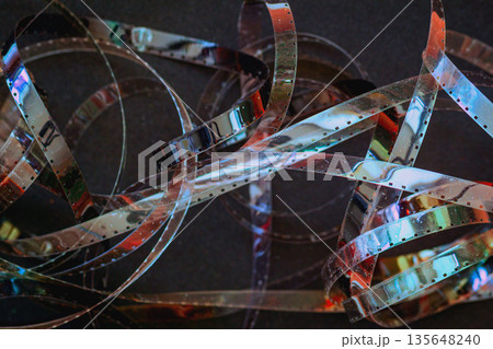 Film Strip Tangle. Tangled film strips with vibrant reflections and cinematic tones. Concept of analog nostalgia, retro media. Retro artistic background 135648240