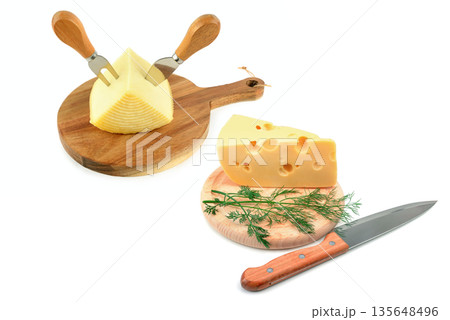 Assorted cheese wedges on wooden boards with serving knives. 135648496