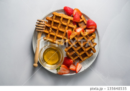 Belgian waffles with strawberries and honey, cup of tea and fresh fruits. Homemade breakfast food. Flat lay Belgian waffles with strawberries and honey, cup of tea and fresh fruits. Homemade breakfast food. Flat lay 135648535