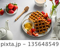 Belgian waffles with strawberries and honey, cup of tea and fresh fruits. Homemade breakfast table setting with tulip flower bouquet 135648549