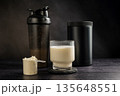 Protein drink in a glass with protein shaker and tube on dark background. Body building, muscle growth and food supplement concept 135648551