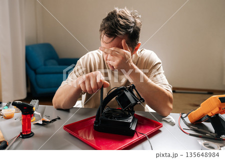 Man struggling with complex computer cooling system repair, feeling frustrated and stressed while troubleshooting difficult technology and hardware issues. Concept of technical support, maintenance. 135648984