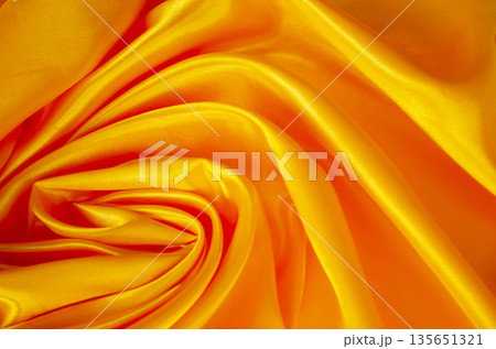 Smooth golden silk background with gentle linear folds creating a refined and elegant abstract texture. 135651321