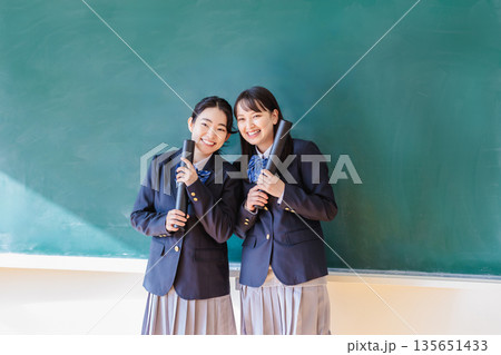 黒板の前で卒業証書を持つ女子生徒 135651433