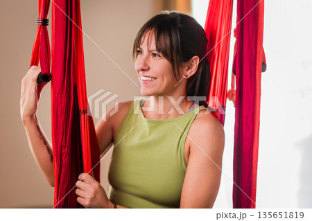 Woman smiling during aerial yoga hammock workout 135651819
