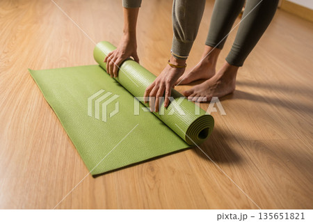 Woman unrolling yoga mat preparing for vinyasa class 135651821