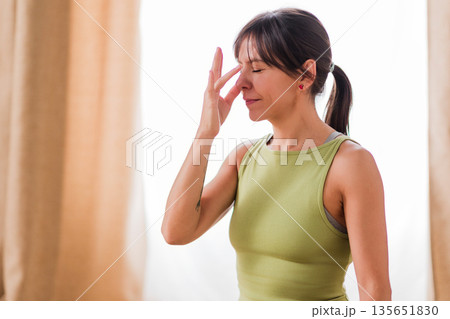 Woman practicing nadi shodhana pranayama alternate nostril breathing Woman practicing nadi shodhana pranayama alternate nostril breathing 135651830