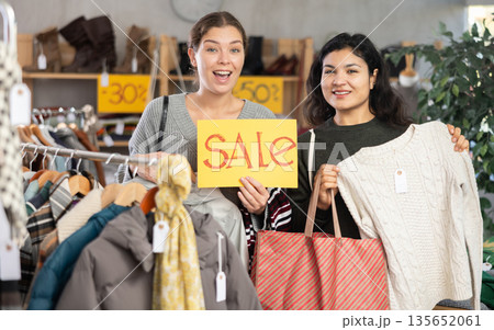 Two women on sale with shoppers and a poster 135652061