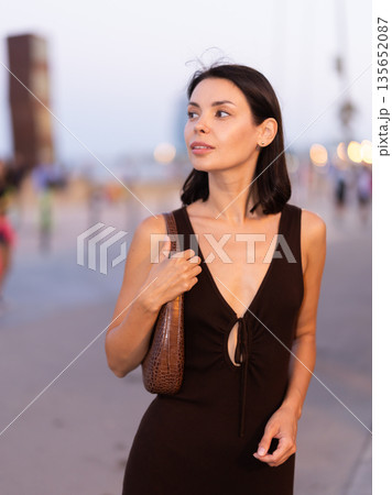 Smiling girl walks around old city district Barceloneta, pedestrian promenade embankment. 135652087
