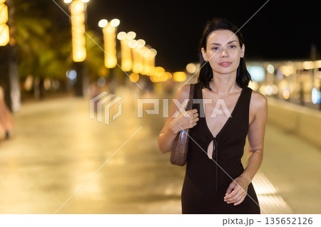 Woman walking along coastal promenade at night in Barcelona 135652126