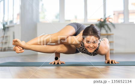 Sporty young girl performing dynamic asanas in yoga studio 135652134