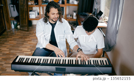 Teacher mentoring student playing digital piano Teacher mentoring student playing digital piano 135652155