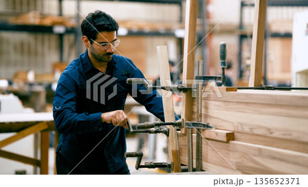Woodworker clamping timber pieces in workshop 135652371