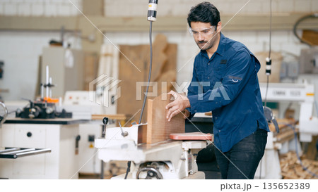 Woodworker using woodworking machine in carpentry workshop Woodworker using woodworking machine in carpentry workshop 135652389