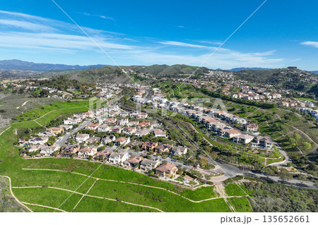 Aerial view over San Juan Capistrano, California, featuring the historic mission, library, sports courts, and an Amtrak train pulling into the downtown station. 135652661