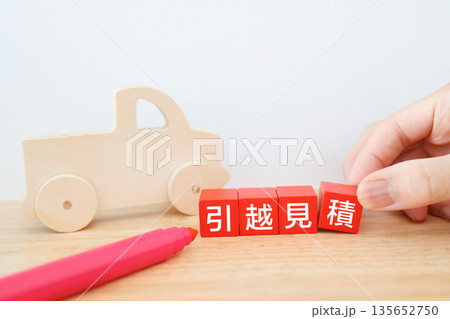 引越し見積もりを表す赤い木製ブロックとトラックのおもちゃ。 引越し見積もりを表す赤い木製ブロックとトラックのおもちゃ。 135652750